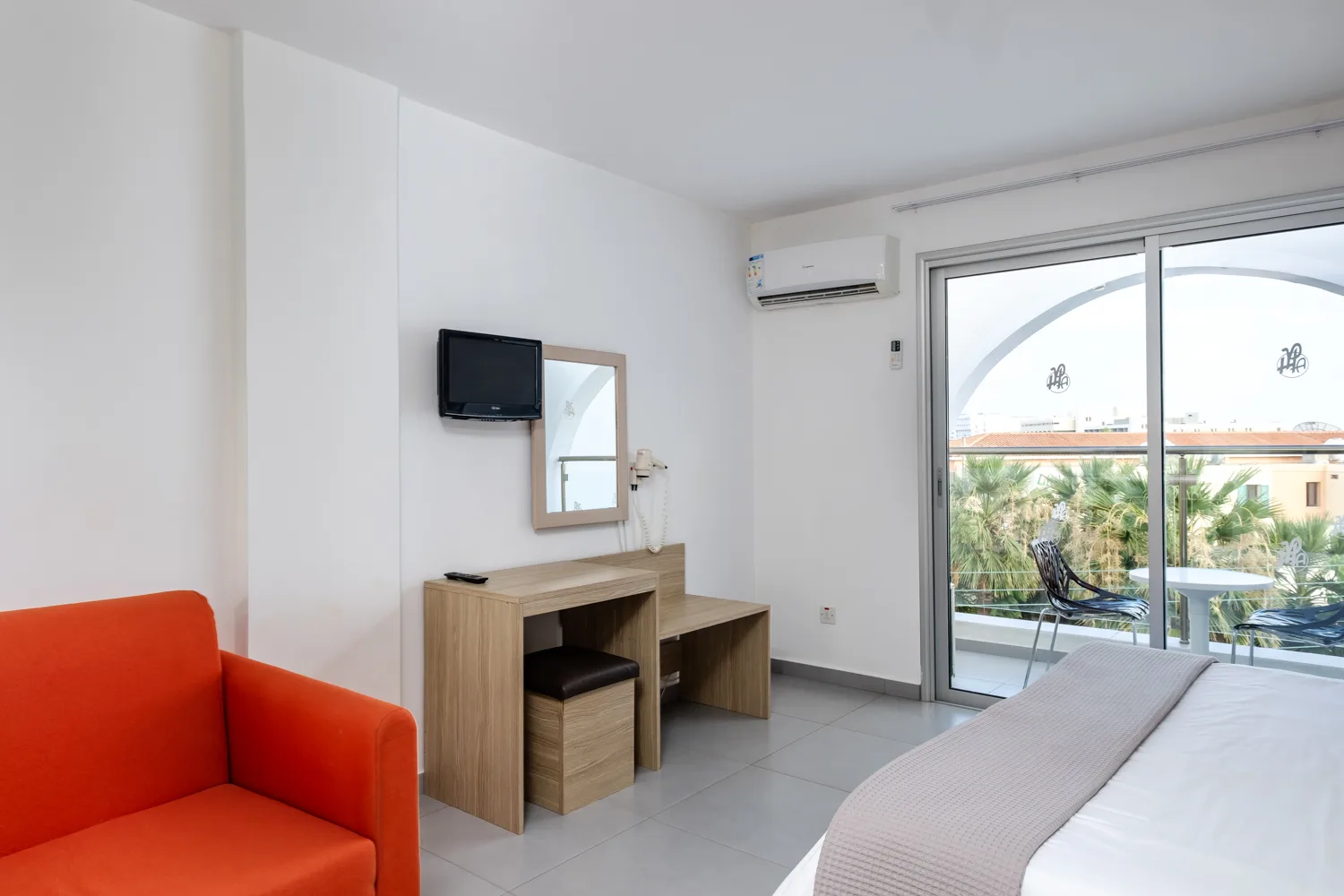 Deluxe studio with an orange armchair and balcony doors